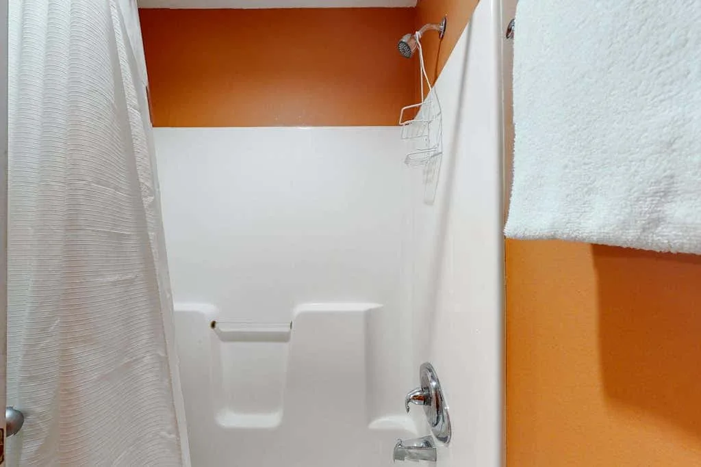 A bathroom shower with a curtain, wall-mounted showerhead, and built-in shelves.