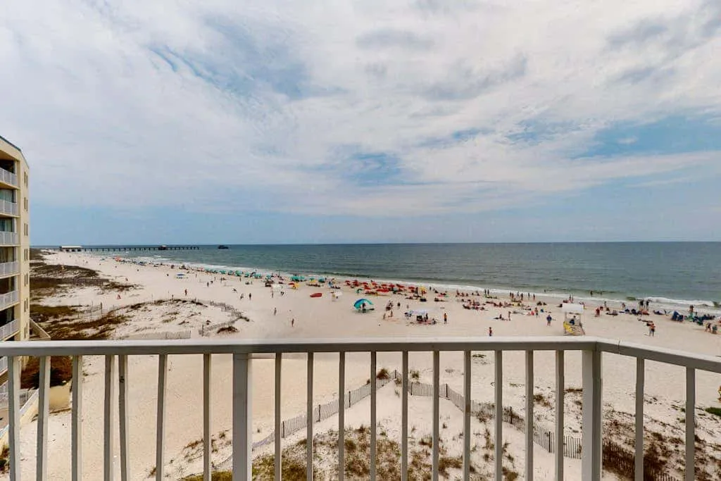 A balcony overlooks a sandy beach and the ocean.
