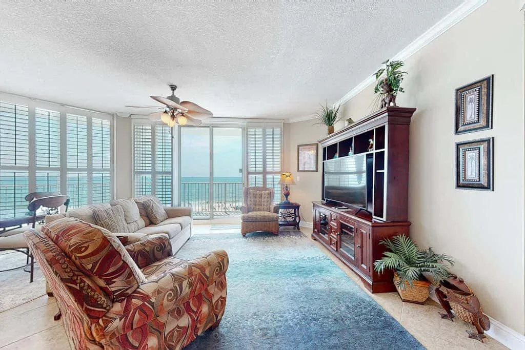 Living room with seating, a television, and large windows overlooking the water.