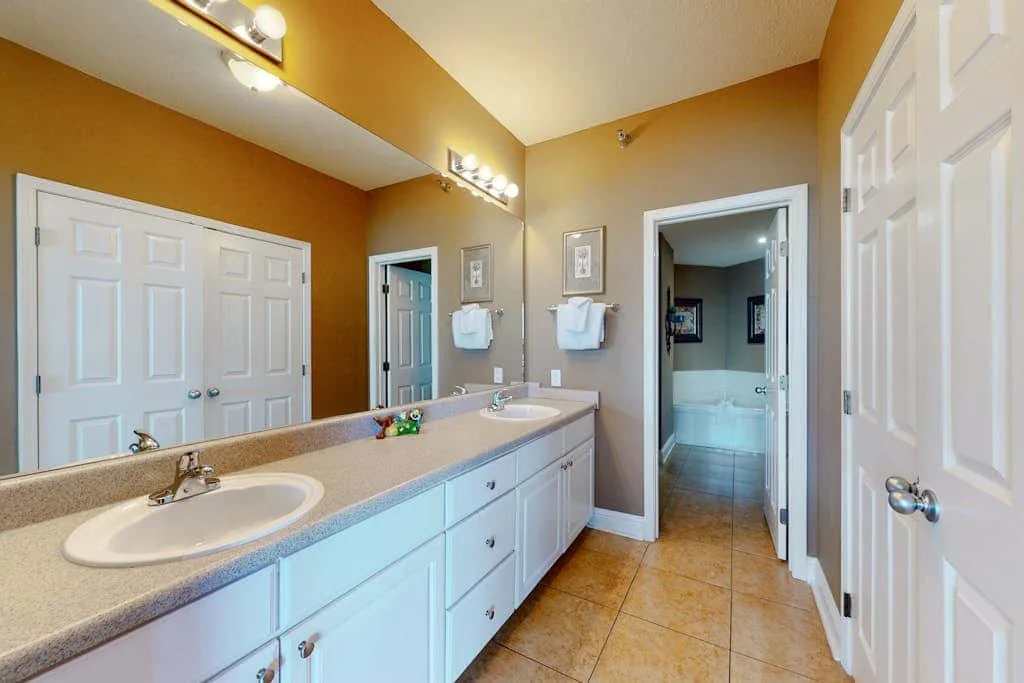 A bathroom vanity with sinks and a doorway leading to a shower.