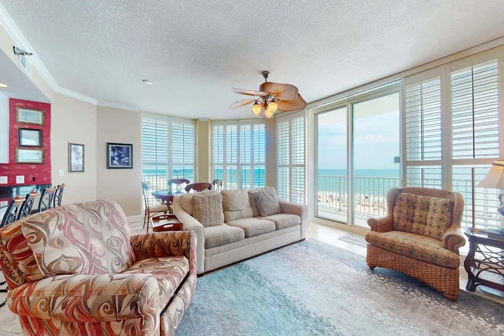 A bright living room with seating beside wide windows overlooking the water.