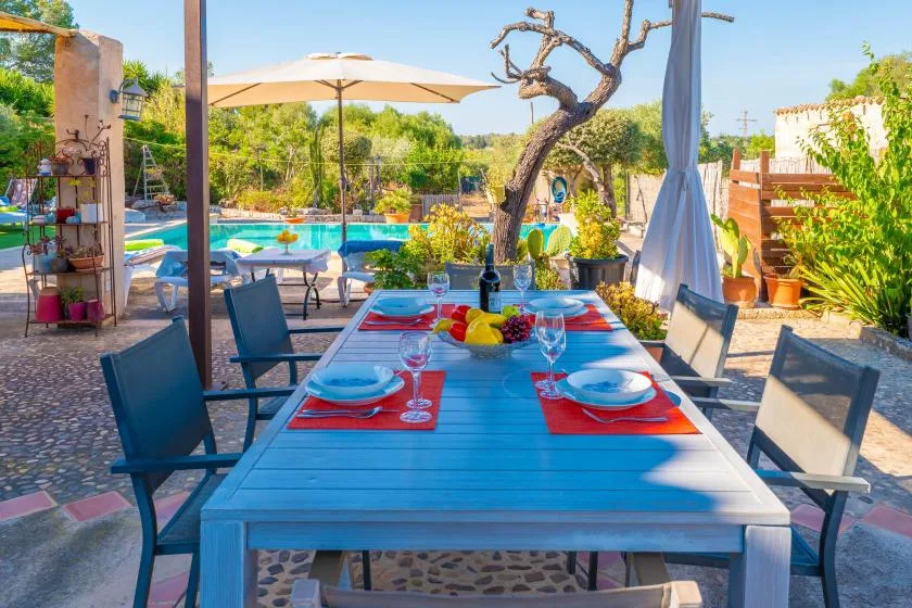 Una zona de comedor al aire libre con una mesa puesta junto a una piscina.