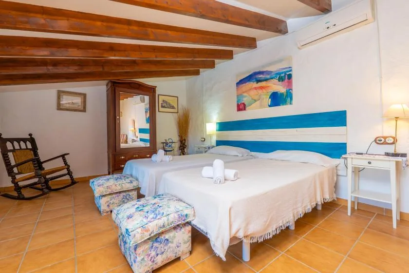 Un dormitorio con dos camas, una mecedora y vigas de madera expuestas en el techo.