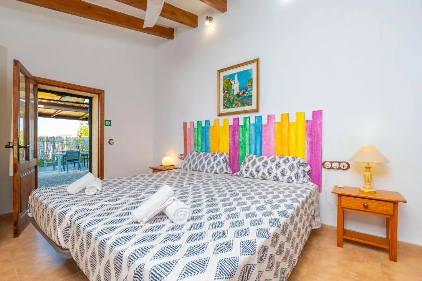 Un dormitorio con dos camas, paneles de colores en la pared y una puerta abierta.