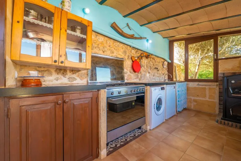 Una cocina rústica con armarios de madera, un horno y una lavadora.