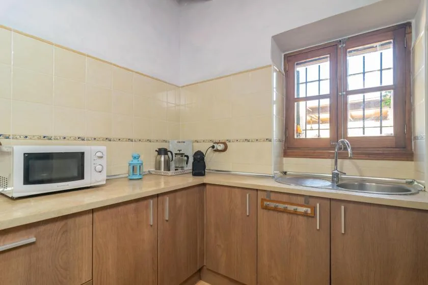 Una cocina con gabinetes de madera, una encimera y un fregadero bajo una ventana.