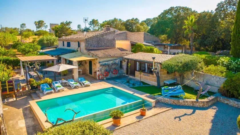 Una piscina exterior está junto a un edificio bajo y jardines.