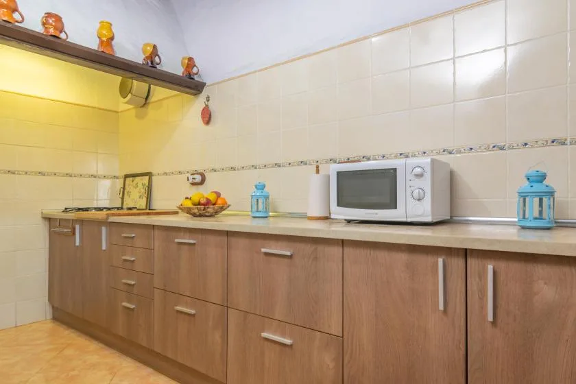 Una cocina con gabinetes de madera, una encimera y un microondas.