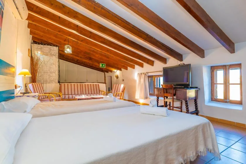 Un dormitorio con dos camas, vigas de madera a la vista y un televisor.