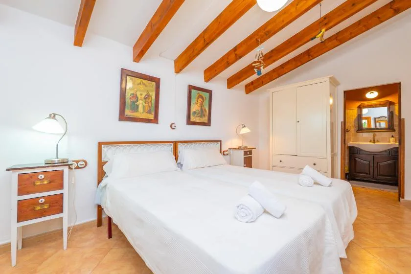 Un dormitorio luminoso con una cama grande bajo vigas de madera vistas.