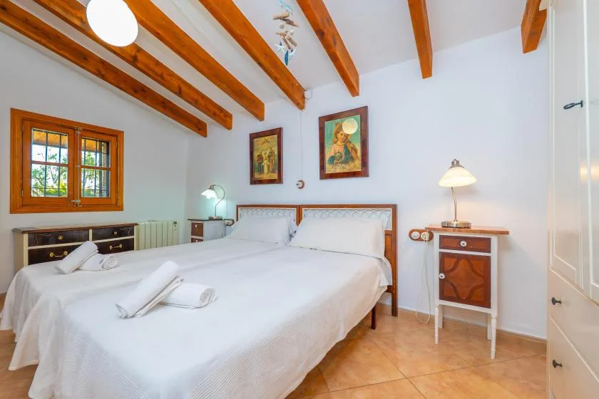 Un dormitorio con una cama grande, vigas de madera en el techo y una ventana.