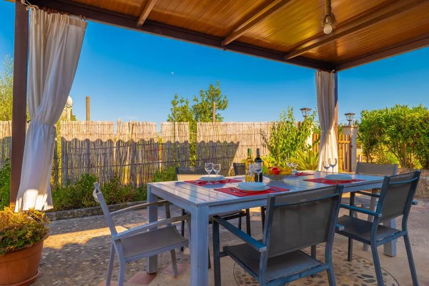 Una zona exterior cubierta para comer tiene una mesa bajo un techo de madera.