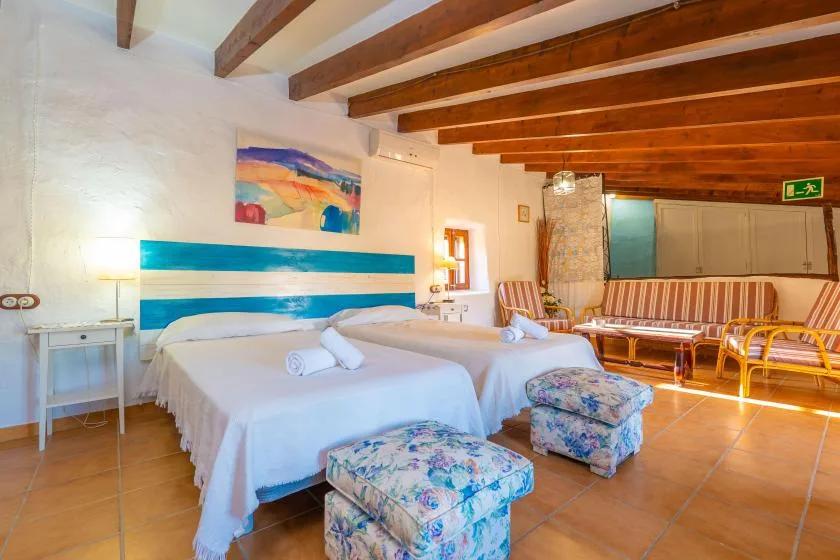 Un dormitorio con dos camas, arte colorido y una zona de estar.