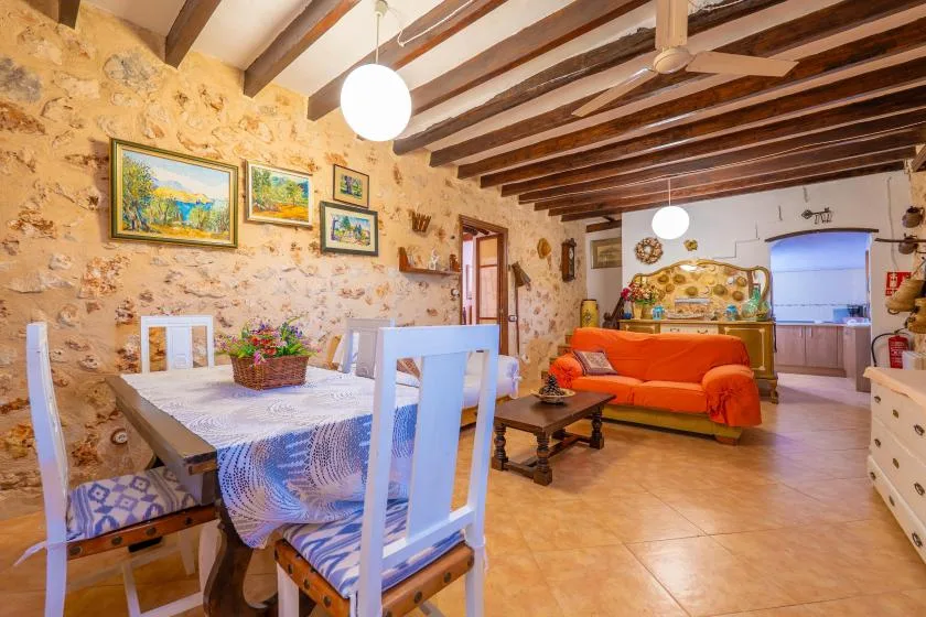 Un comedor y sala de estar rústicos con una mesa puesta y asientos naranjas.