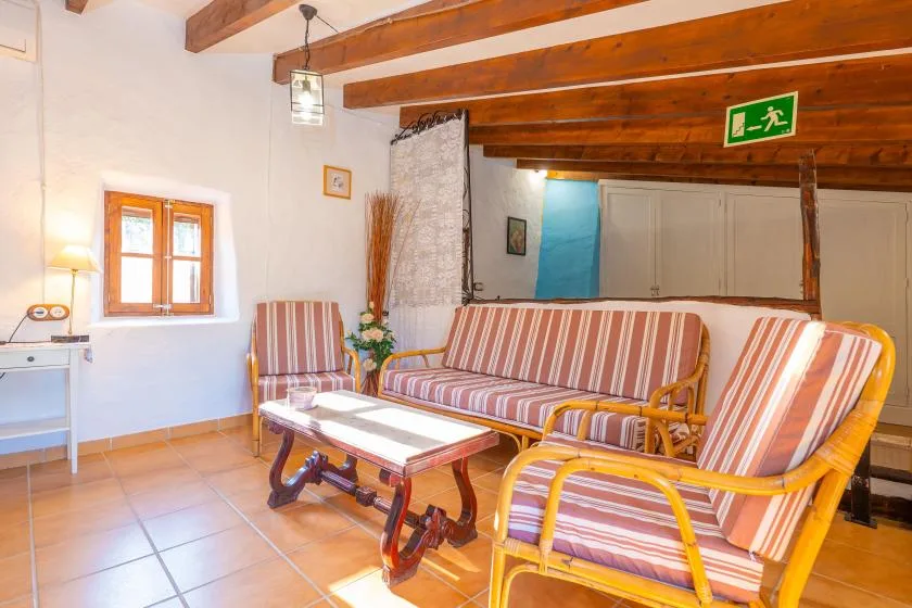 Una sala de estar con asientos a rayas, una mesa baja y vigas de madera expuestas.