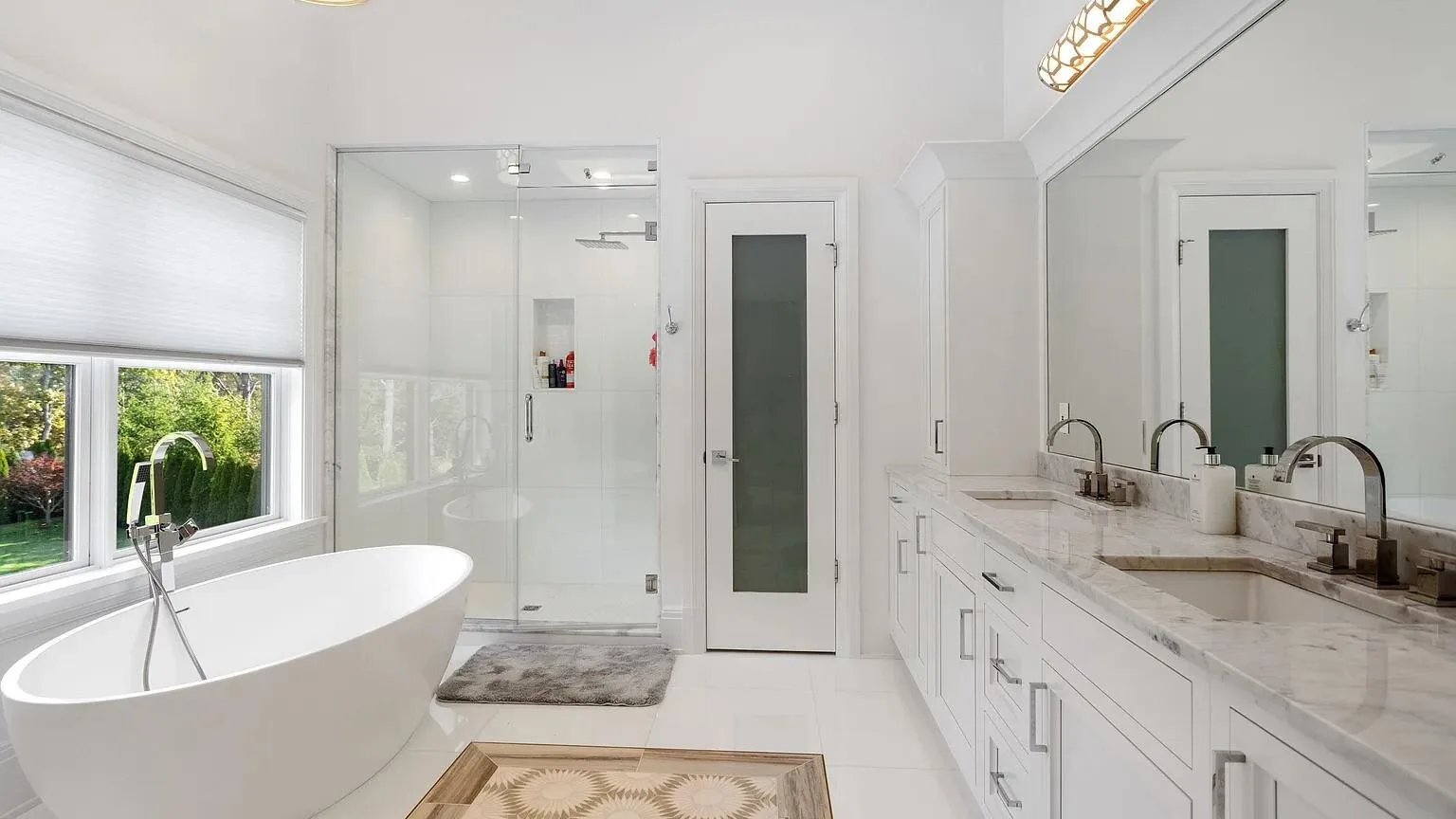 Un baño luminoso con una bañera independiente y un tocador largo.