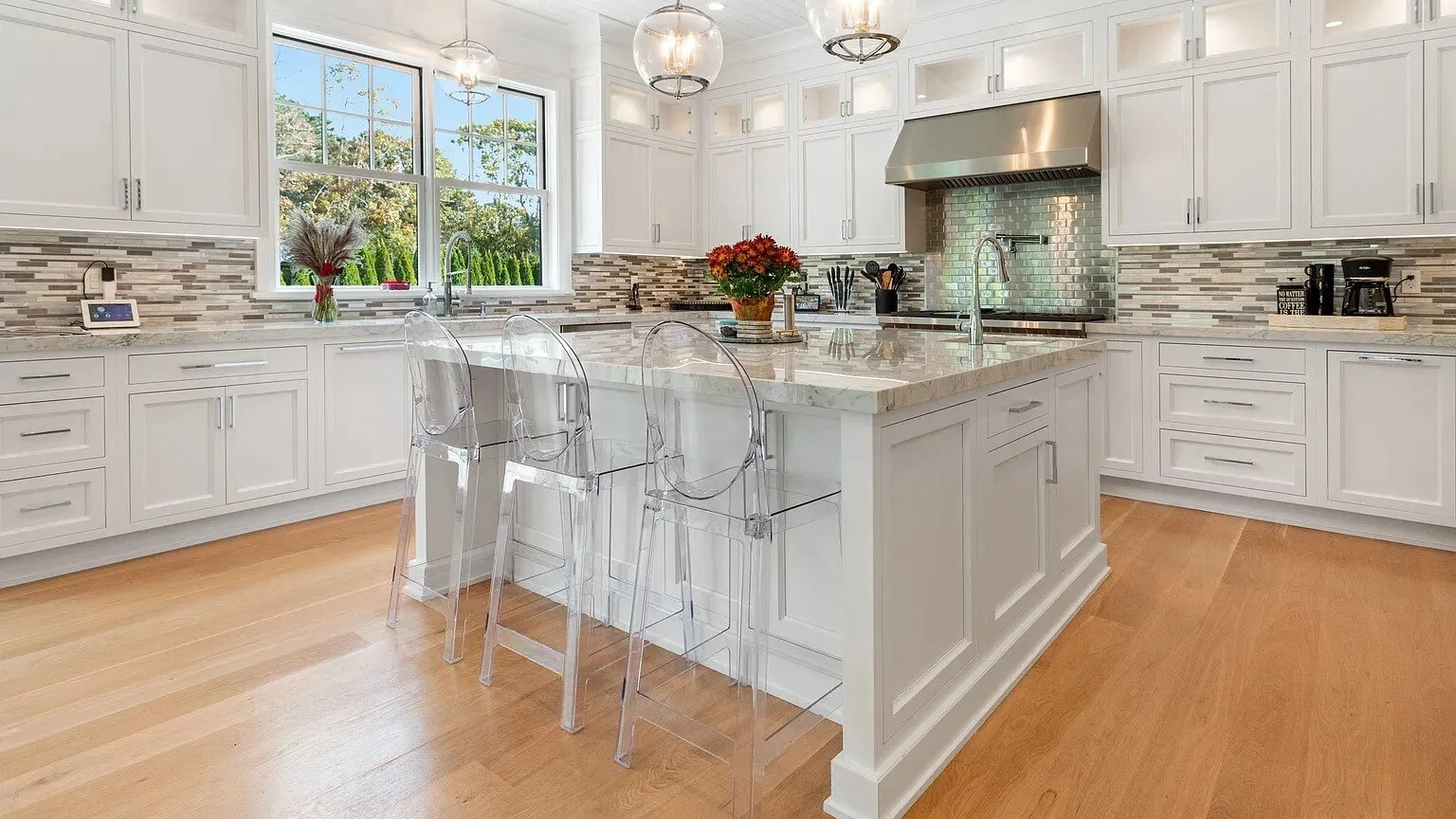Una cocina luminosa con gabinetes blancos y una isla central con asientos.