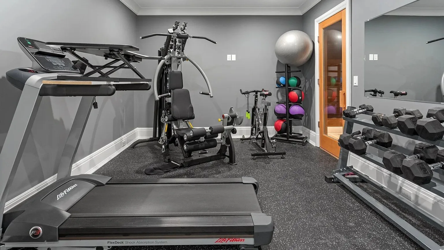 Un gimnasio en casa con equipos de ejercicio y una pared de espejos.