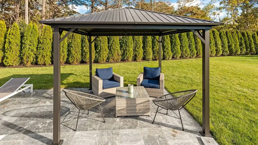 Una zona de estar exterior cubierta con sillas y una mesa baja en un patio pavimentado.