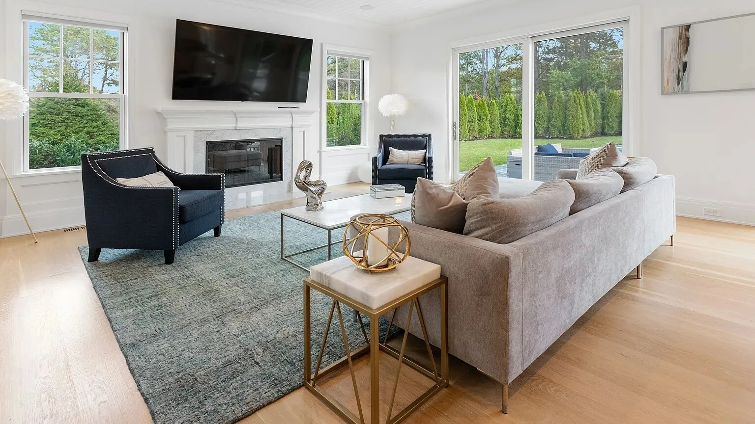 A bright living room with seating around a fireplace and large windows.