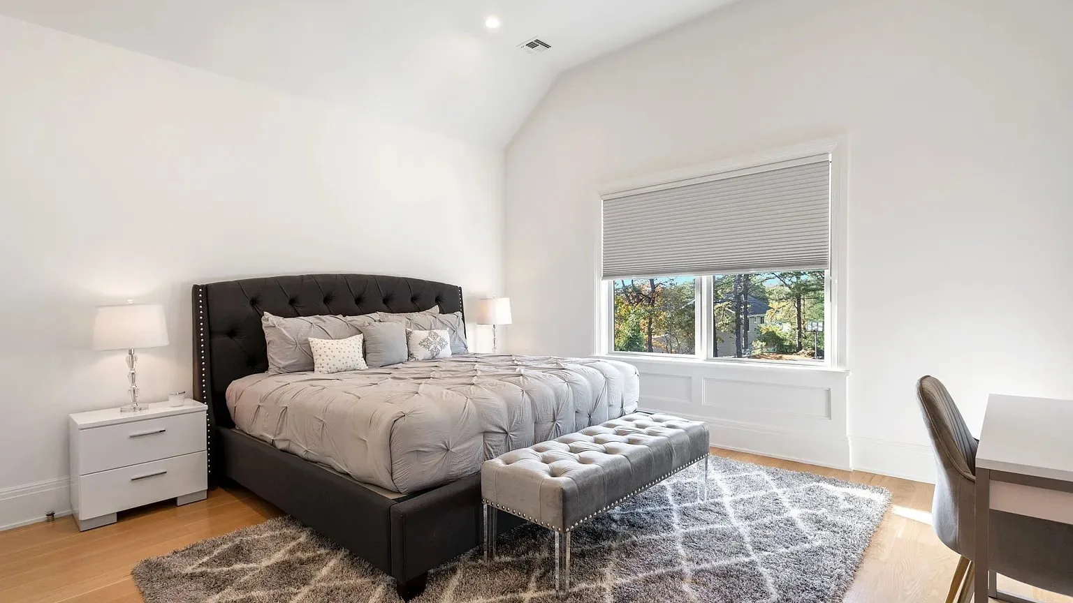 Un dormitorio luminoso con una cama grande, un banco y una ventana.