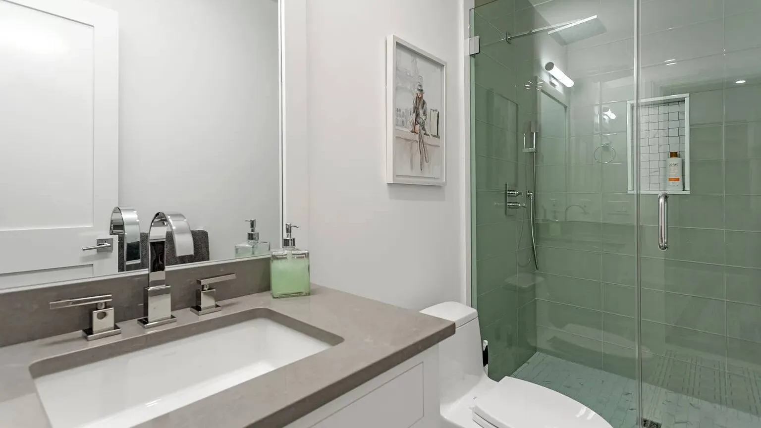 Un baño moderno con una amplia encimera de lavabo y una ducha de vidrio.