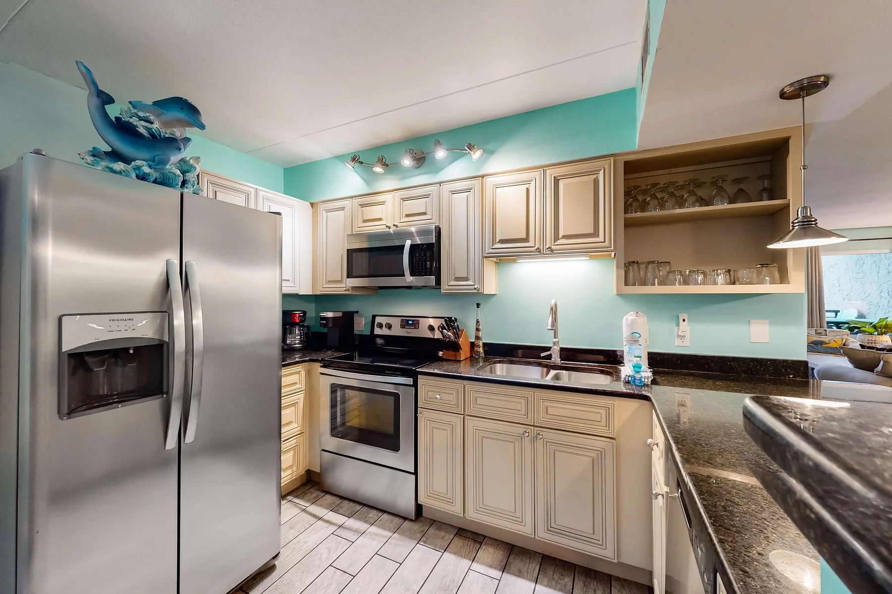 A kitchen with light-colored cabinets, stainless steel appliances, and dark countertops.