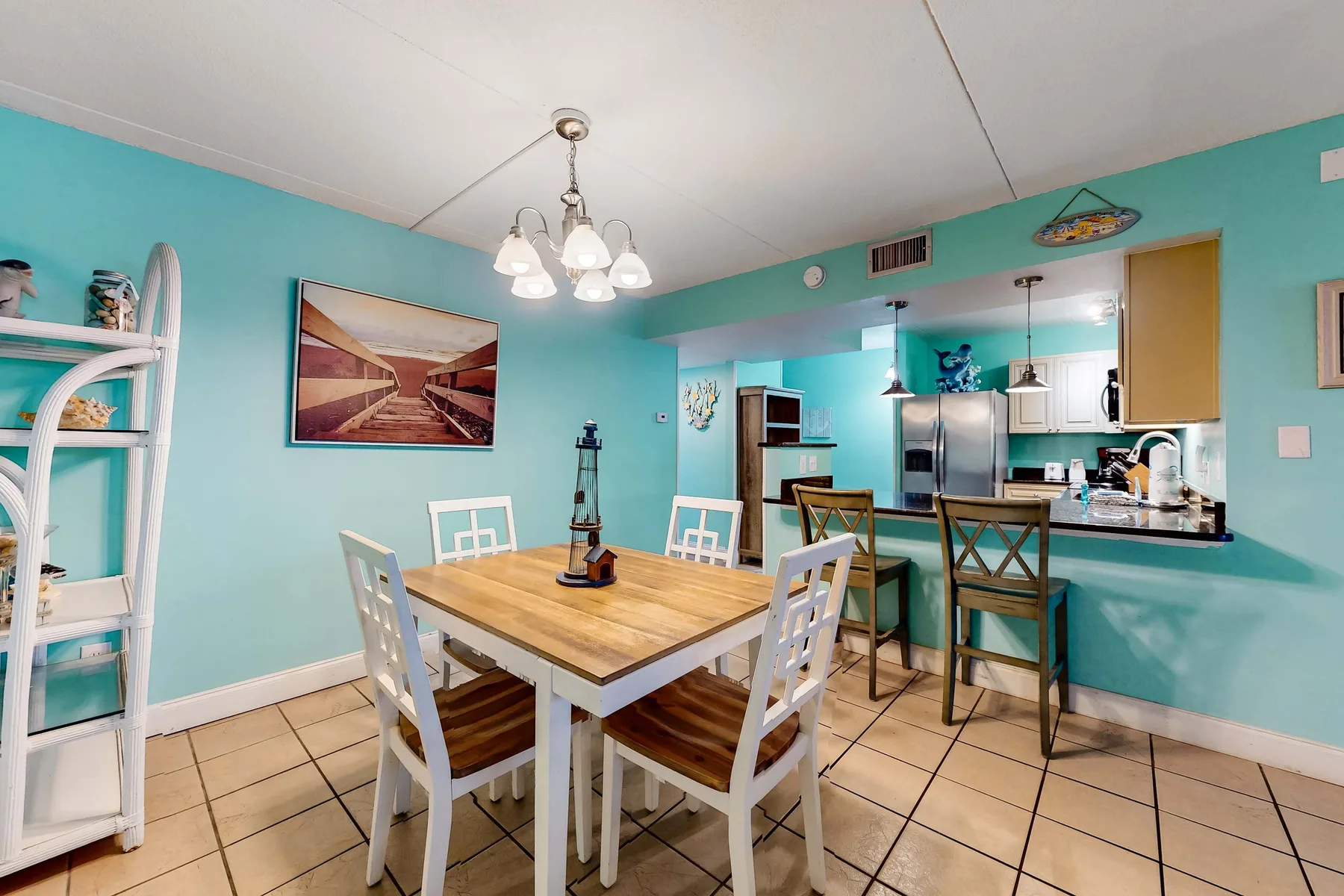 A dining area with a wooden table and chairs beside an open kitchen.