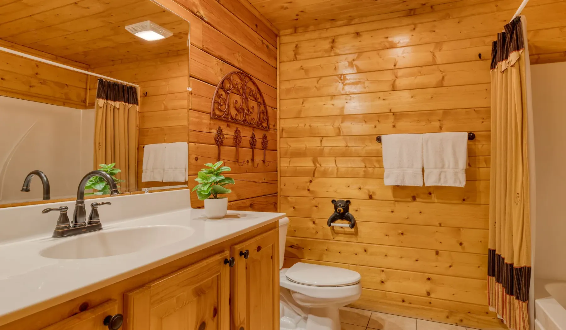 Un baño revestido de madera con lavabo, inodoro y cortina de ducha.