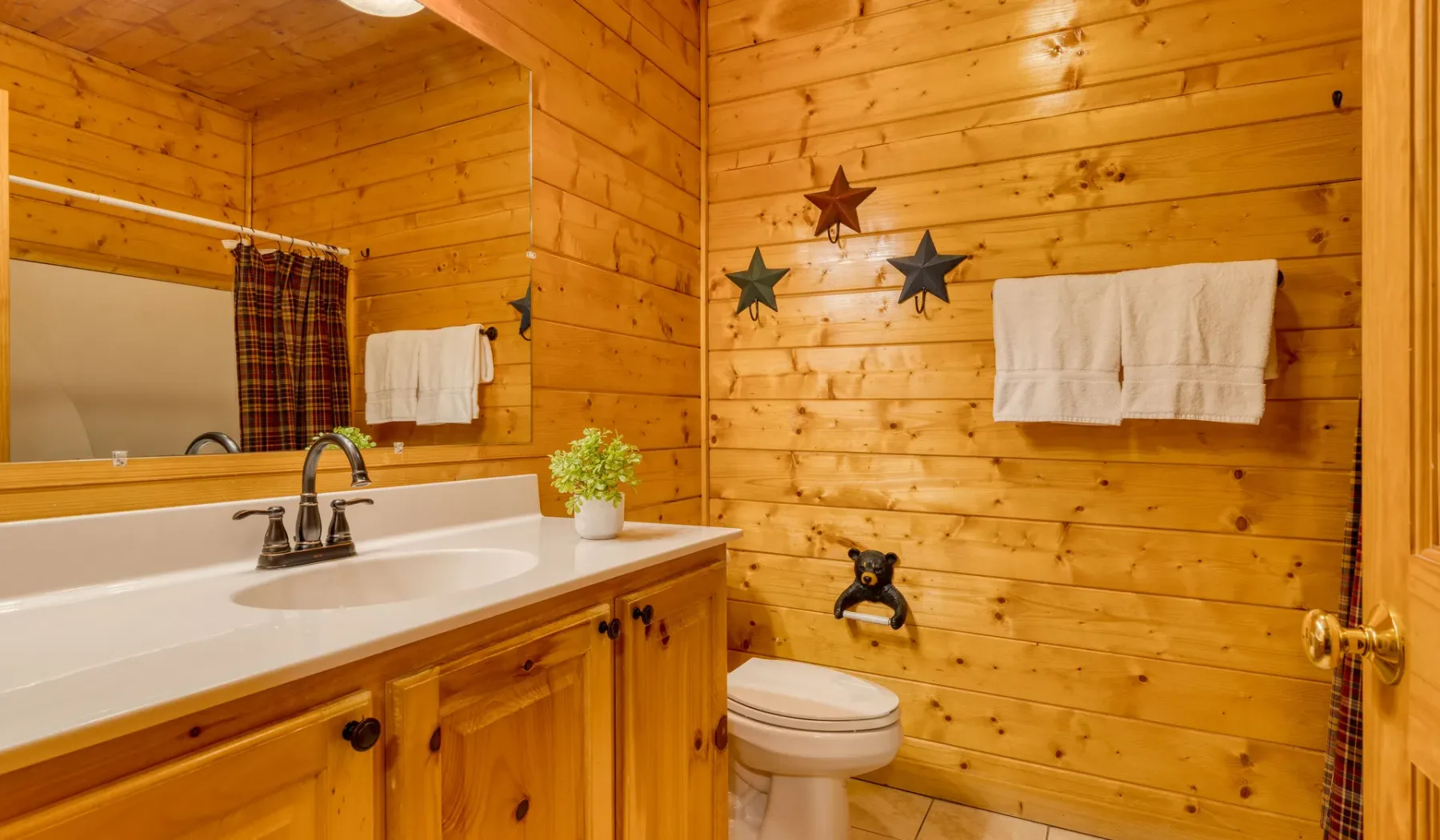 Un baño revestido de madera con lavabo, inodoro y toallas colgadas en la pared.