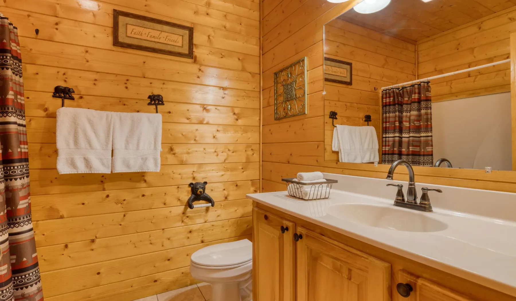 Baño revestido de madera con lavabo, inodoro y cortina de ducha.