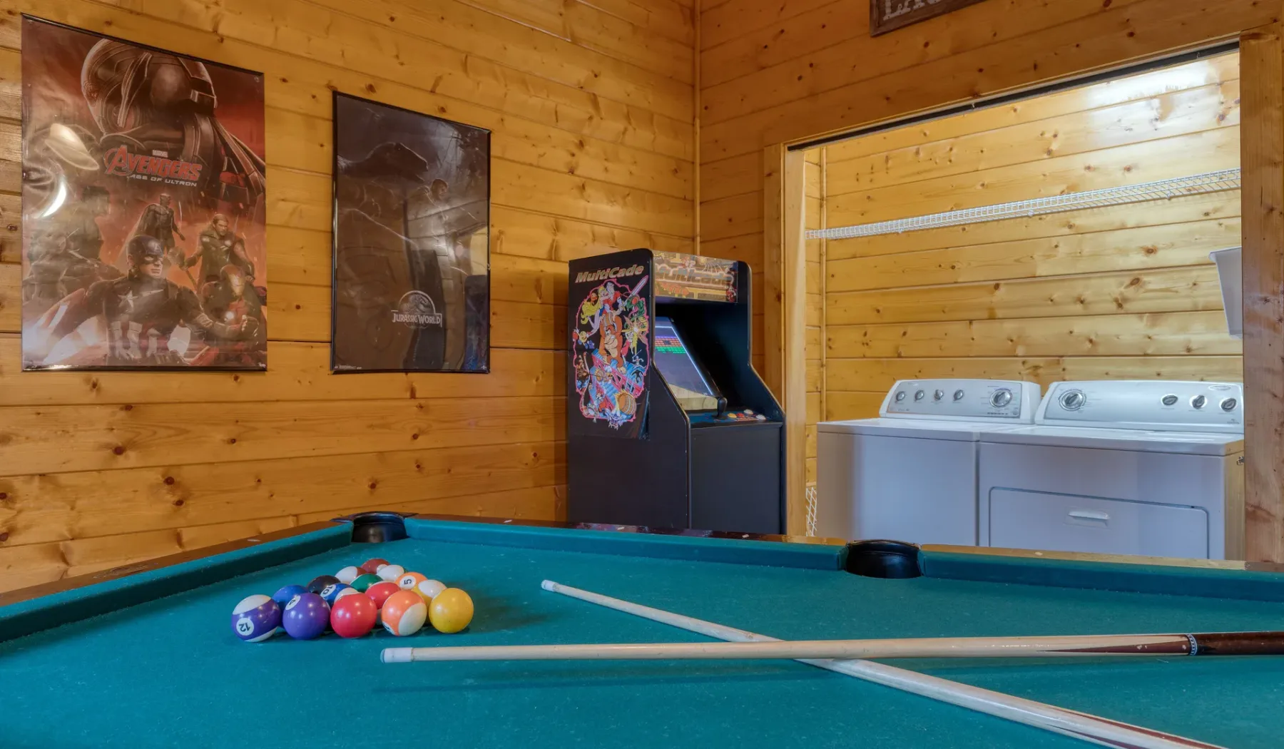 Sala de juegos con mesa de billar y máquina recreativa.