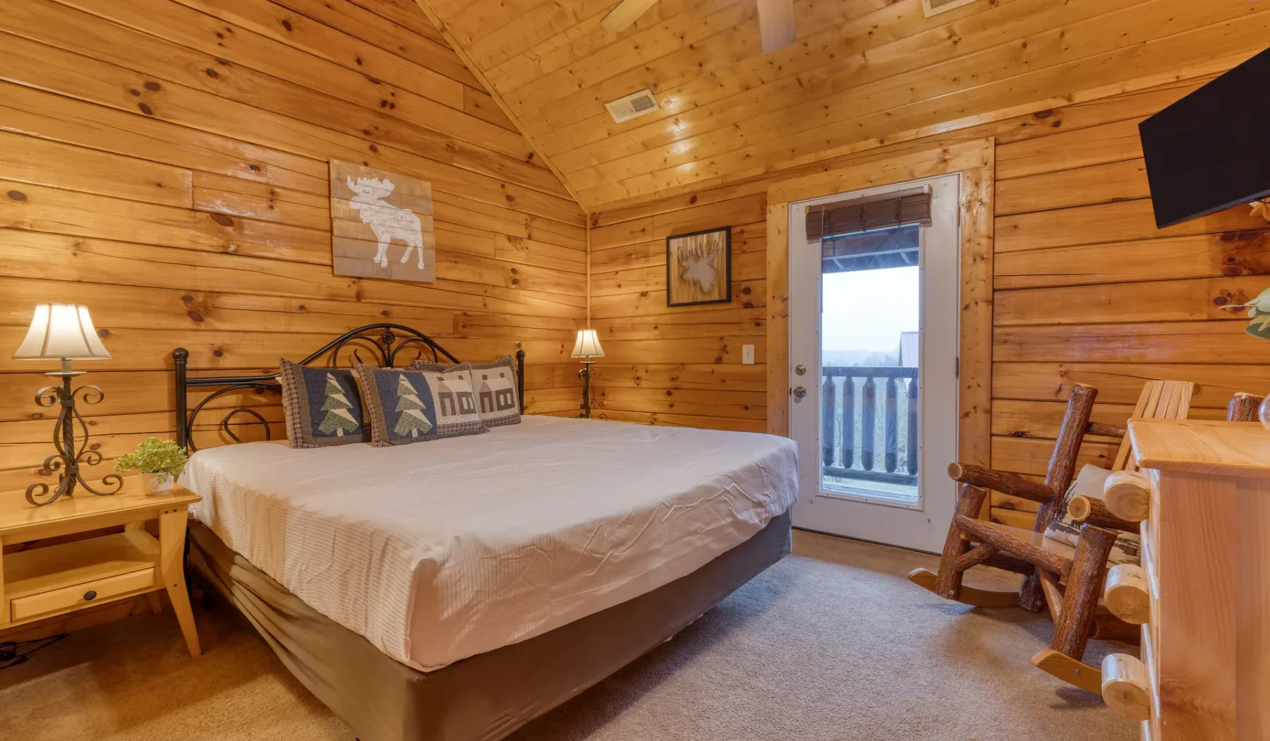 Un dormitorio con una cama grande, paredes revestidas de madera y una puerta de vidrio que da a un balcón.