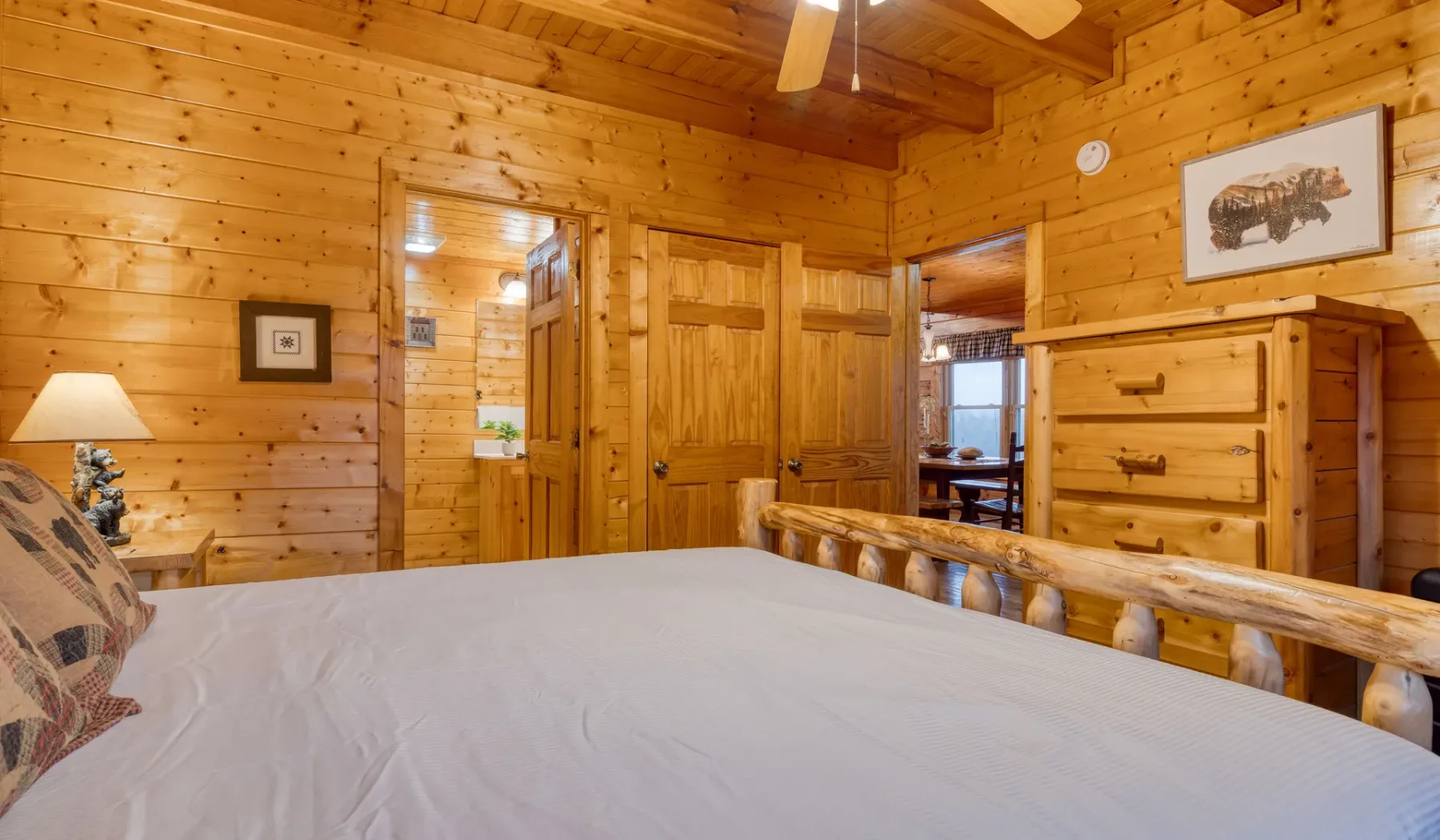 Un dormitorio con una cama, paredes de madera y una cómoda.