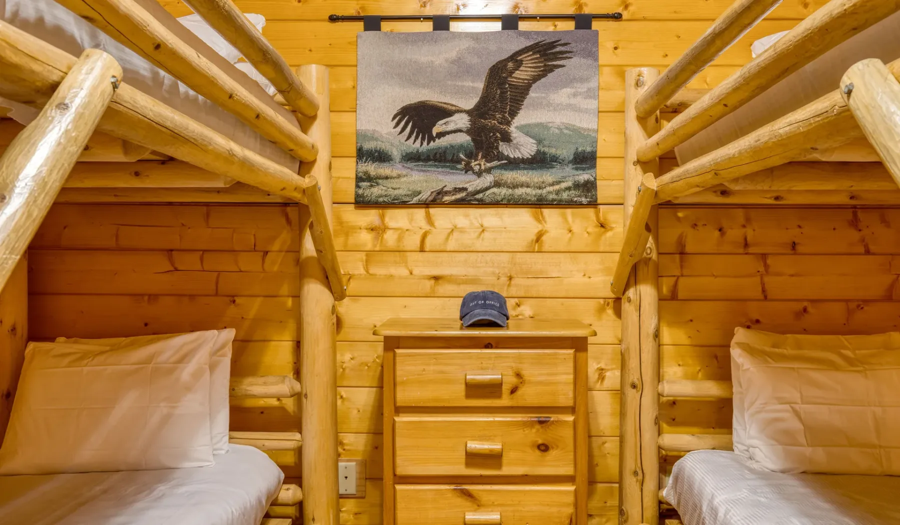 Dormitorio con paredes de madera, dos camas y una cómoda.
