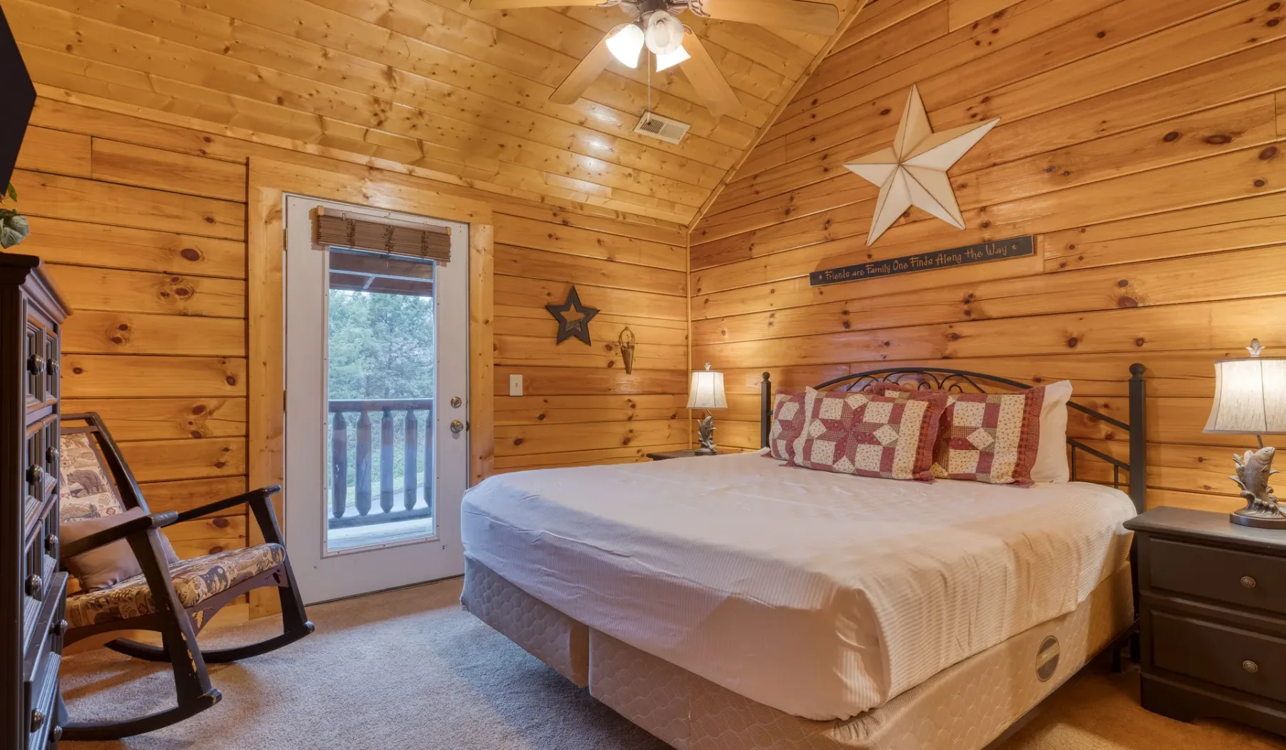 Un dormitorio con paredes de madera, una cama, mesas de noche y una puerta de vidrio.