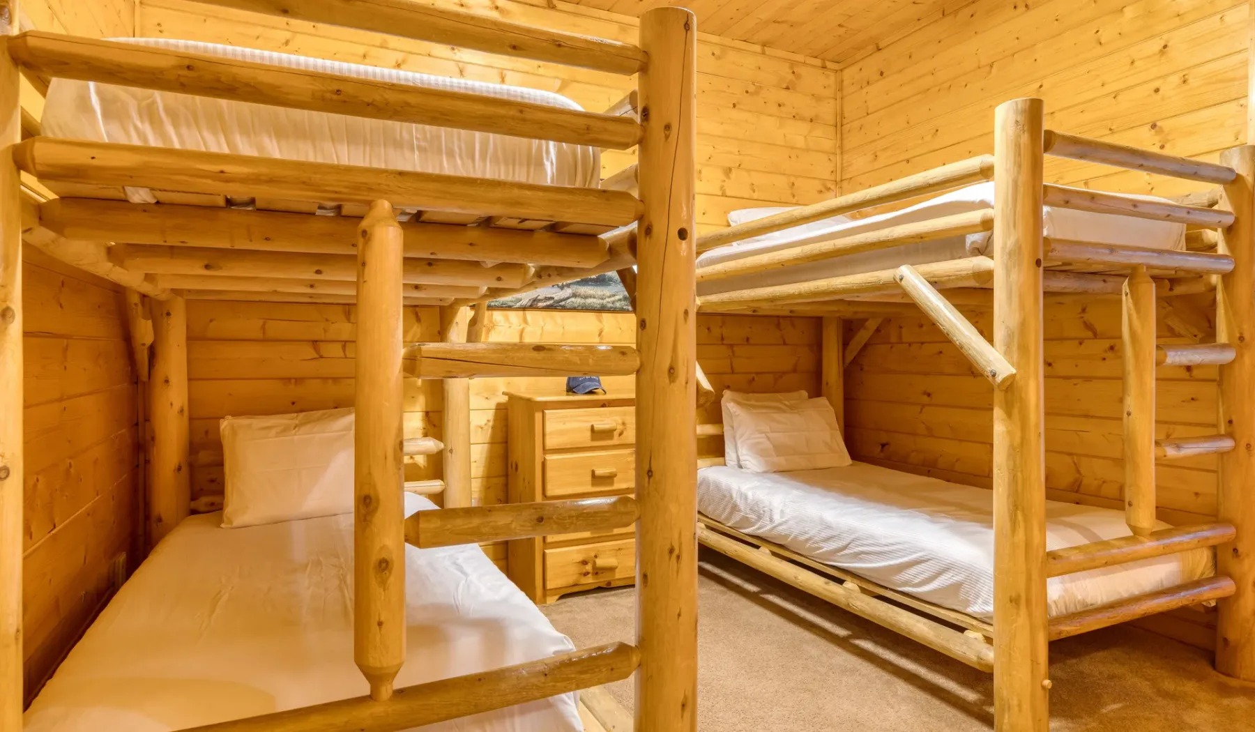 Un dormitorio con literas de madera, ropa de cama clara y una pequeña mesita.