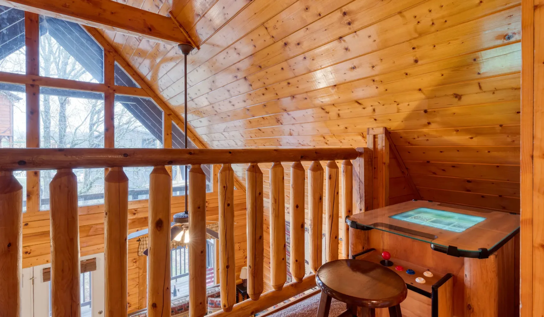 Interior de un altillo de madera con barandilla y una bañera de hidromasaje.