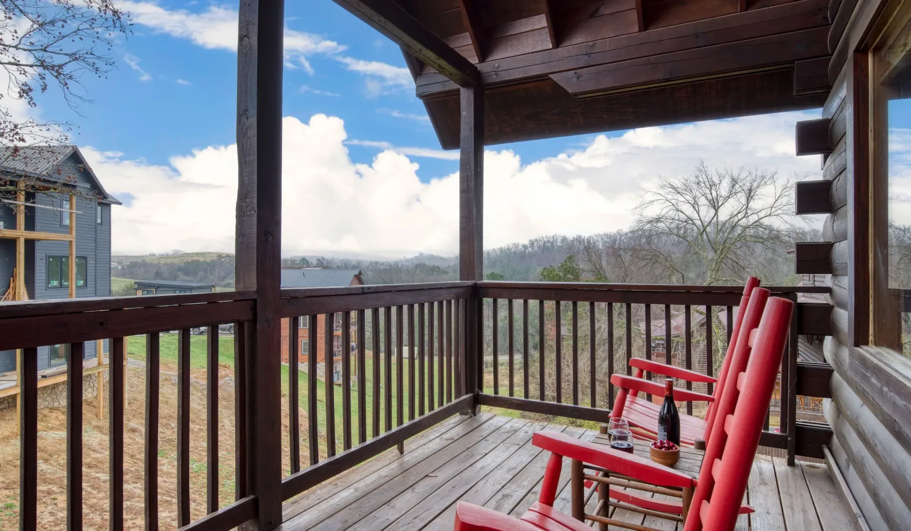 Una terraza de madera cubierta con asientos rojos da a un paisaje boscoso.