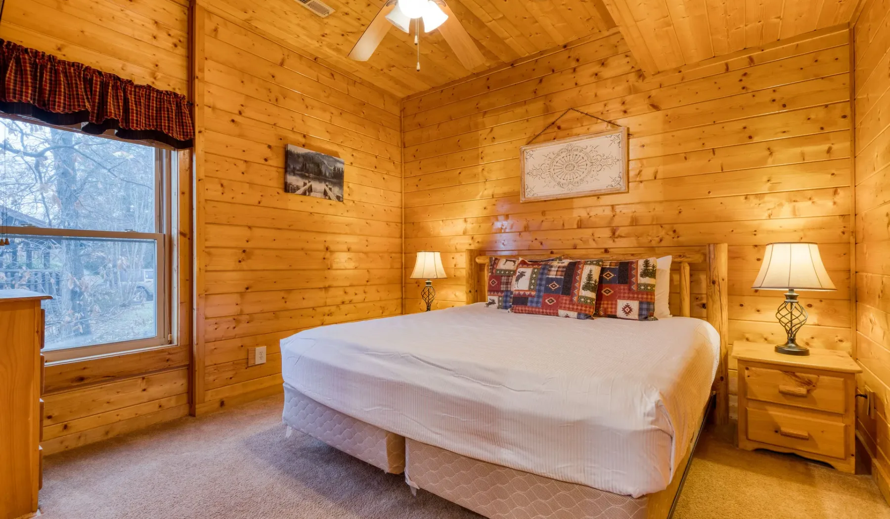 Un dormitorio revestido de madera con una cama, mesas de noche y una ventana.