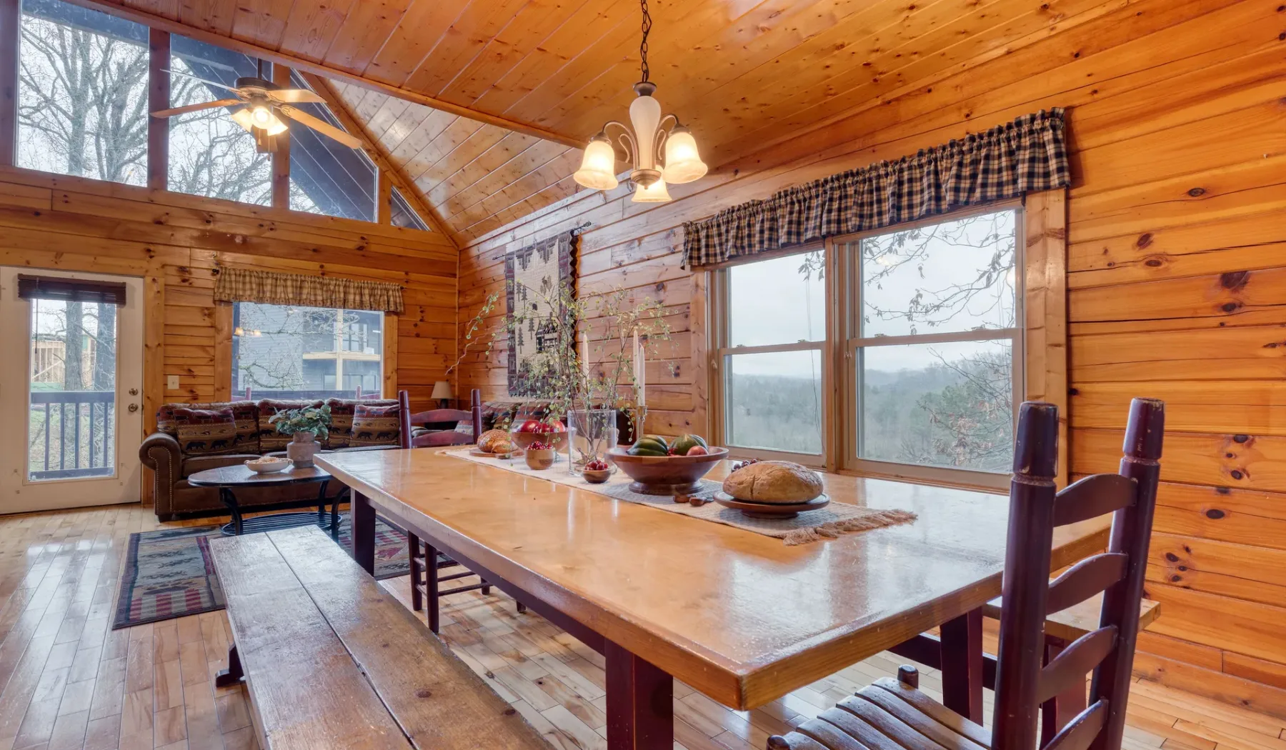 Un comedor revestido de madera con una mesa larga junto a grandes ventanas.