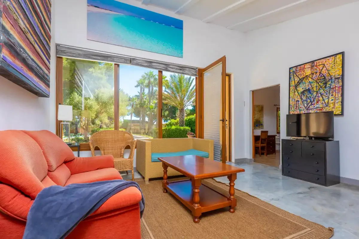 A living room with seating, a coffee table, and large windows overlooking greenery.
