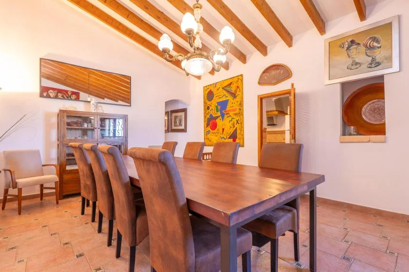 A dining room with a long wooden table, upholstered seating, and exposed ceiling beams.