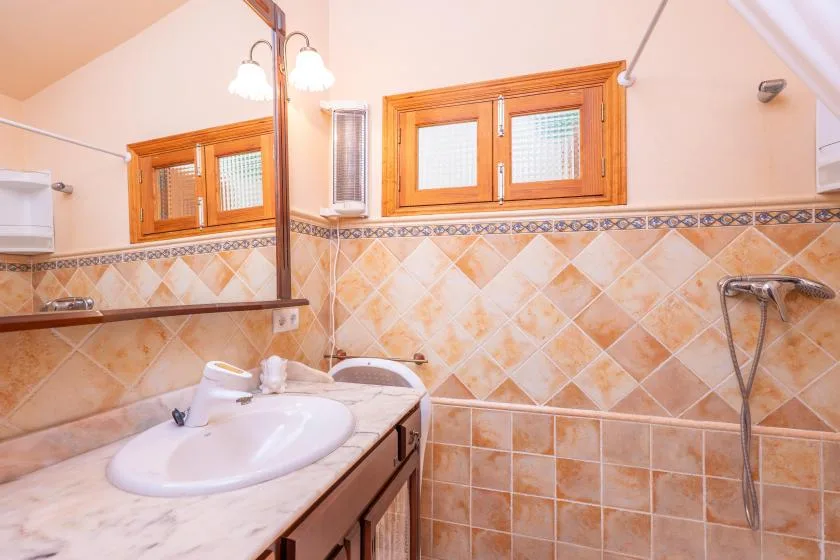 A tiled bathroom with a sink, mirror, and shower fixture.