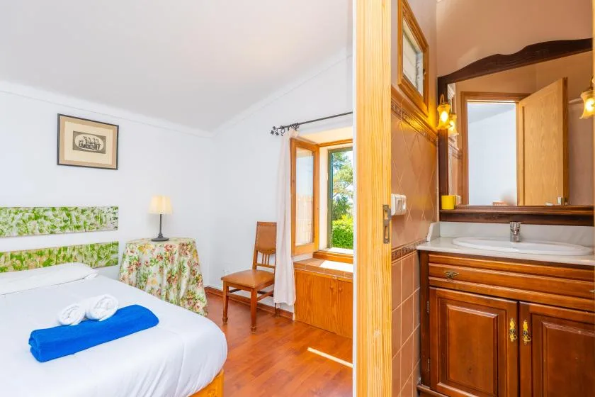 A bedroom beside a bathroom, with a bed and a wooden vanity.