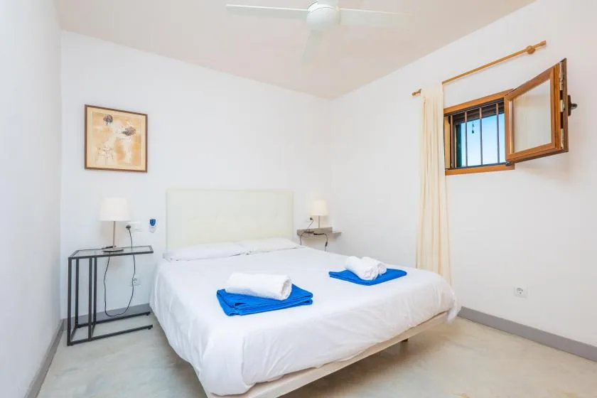 A bedroom with a neatly made bed and an open window.