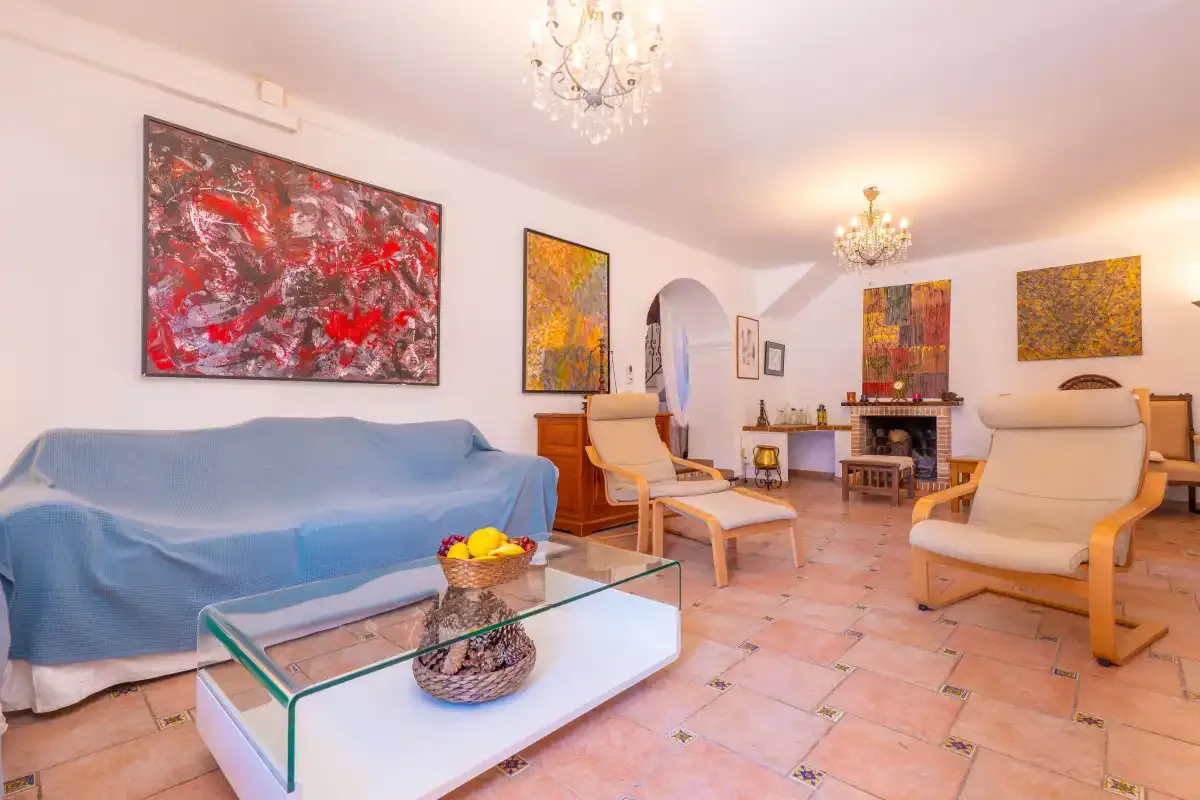 A living room with seating, colorful wall art, and a glass coffee table.