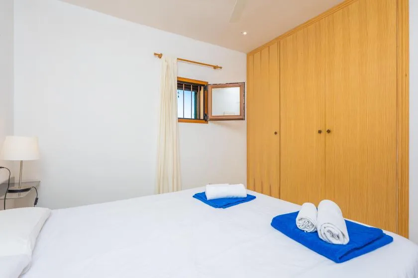 A bedroom with a neatly made bed and wooden wardrobes.