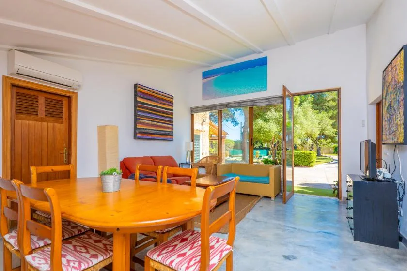 A bright living and dining area opens onto a patio through glass doors.
