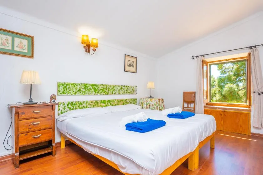 A bright bedroom with a large bed dressed in white linens and blue towels.